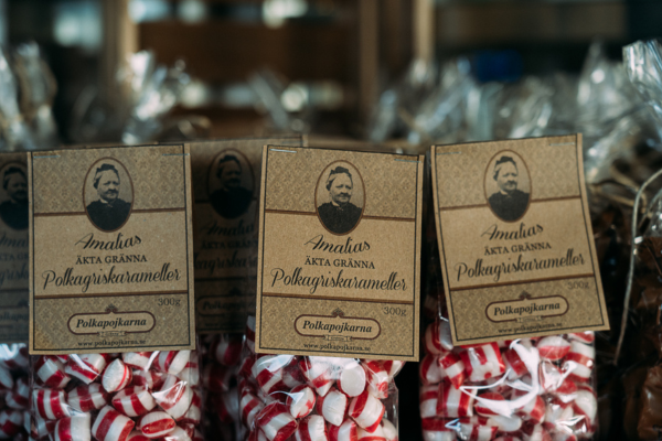 Polkagriskarameller i retro förpackningar med rödvita polkagrisar i bakgrunden
